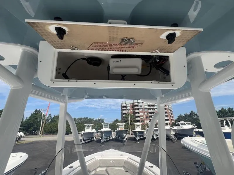 Slide: The Image of 2025 Sea Hunt Ultra 219 boat with open electronics compartment, docked with other boats in background. - 11