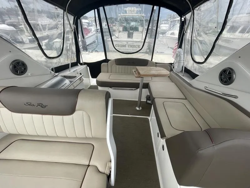 Slide: The Image of 2014 Sea Ray 310 Sundancer interior with seating and table, docked at marina. - 10