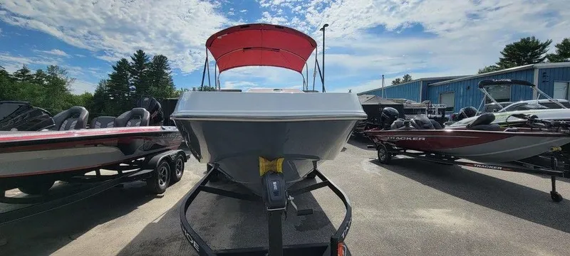Slide: The Image of 2024 Tahoe T21 boat with red canopy on trailer, parked between other boats. - 11