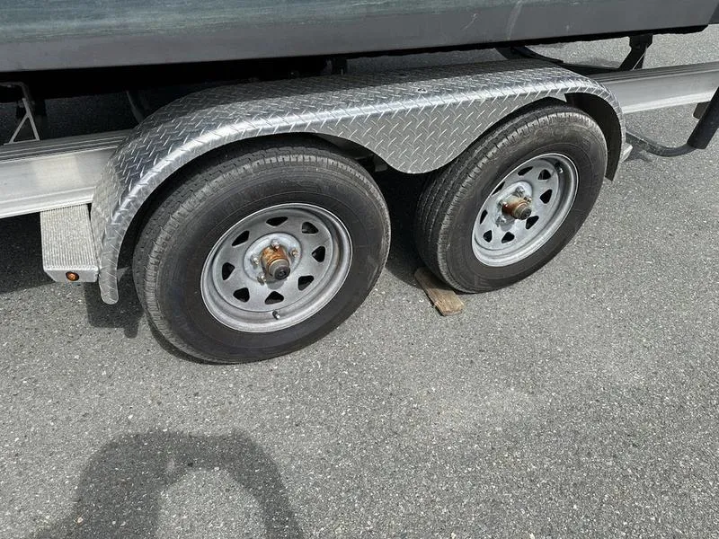 Slide: The Image of 2022 Robalo R242 boat trailer with dual axle wheels on asphalt. - 6