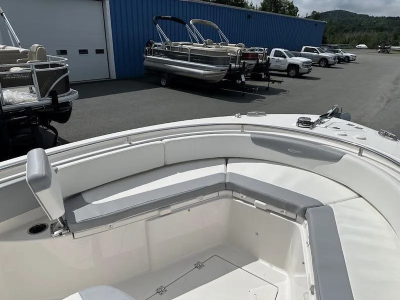 Slide: The Image of 2022 Robalo R242 boat with spacious seating, docked near blue building and parked vehicles. - 9