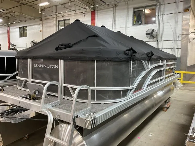 Slide: The Image of 2024 Bennington 20 SVSR pontoon boat with black cover in a warehouse setting. - 11