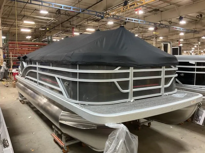 Slide: The Image of 2024 Bennington 20 SVSR pontoon boat in a factory setting, covered with a black tarp. - 6
