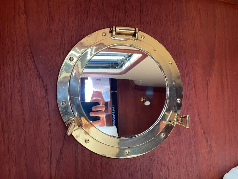 Slide: The Image of Round brass porthole on 1978 CAL 2-39 yacht, reflecting interior cabin view. - 17