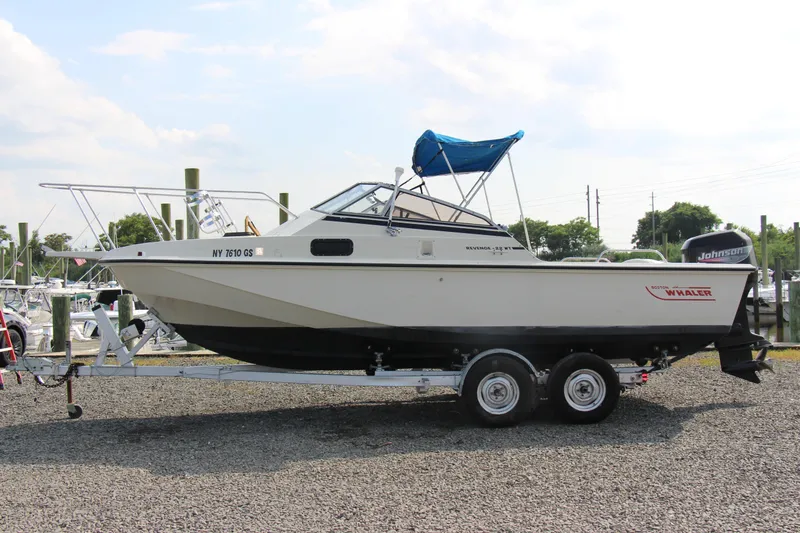 Slide: The Image of 1985 Boston Whaler Revenge 22 boat on a trailer with blue canopy. - 1