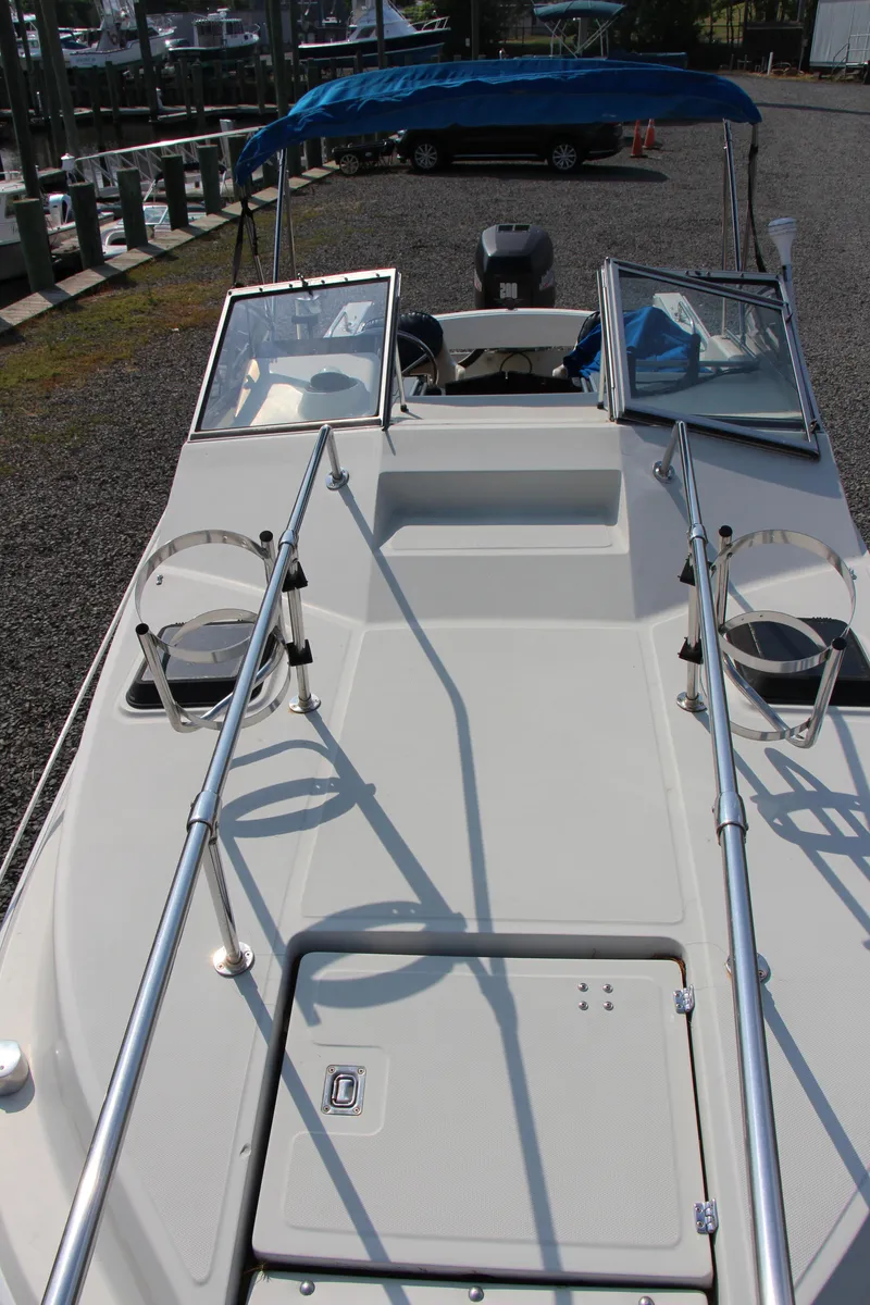 Slide: The Image of 1985 Boston Whaler Revenge 22 boat with open deck and blue canopy. - 12