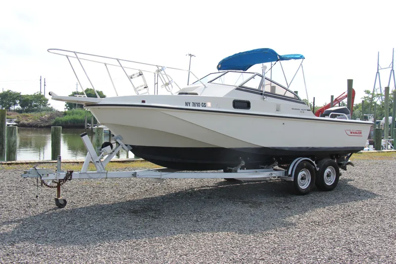 Slide: The Image of 1985 Boston Whaler Revenge 22 boat on a trailer with blue canopy. - 2