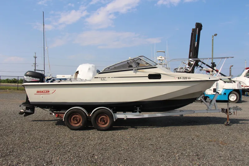 Slide: The Image of 1985 Boston Whaler Revenge 22 boat on a trailer in a marina. - 21