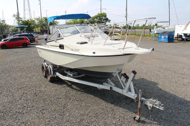 Slide: The Image of 1985 Boston Whaler Revenge 22 boat on a trailer in a parking lot. - 3