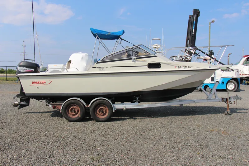 Slide: The Image of 1985 Boston Whaler Revenge 22 boat on a trailer with blue canopy. - 5