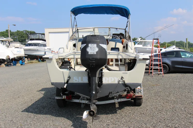 Slide: The Image of 1985 Boston Whaler Revenge 22 boat with outboard motor in a marina. - 7