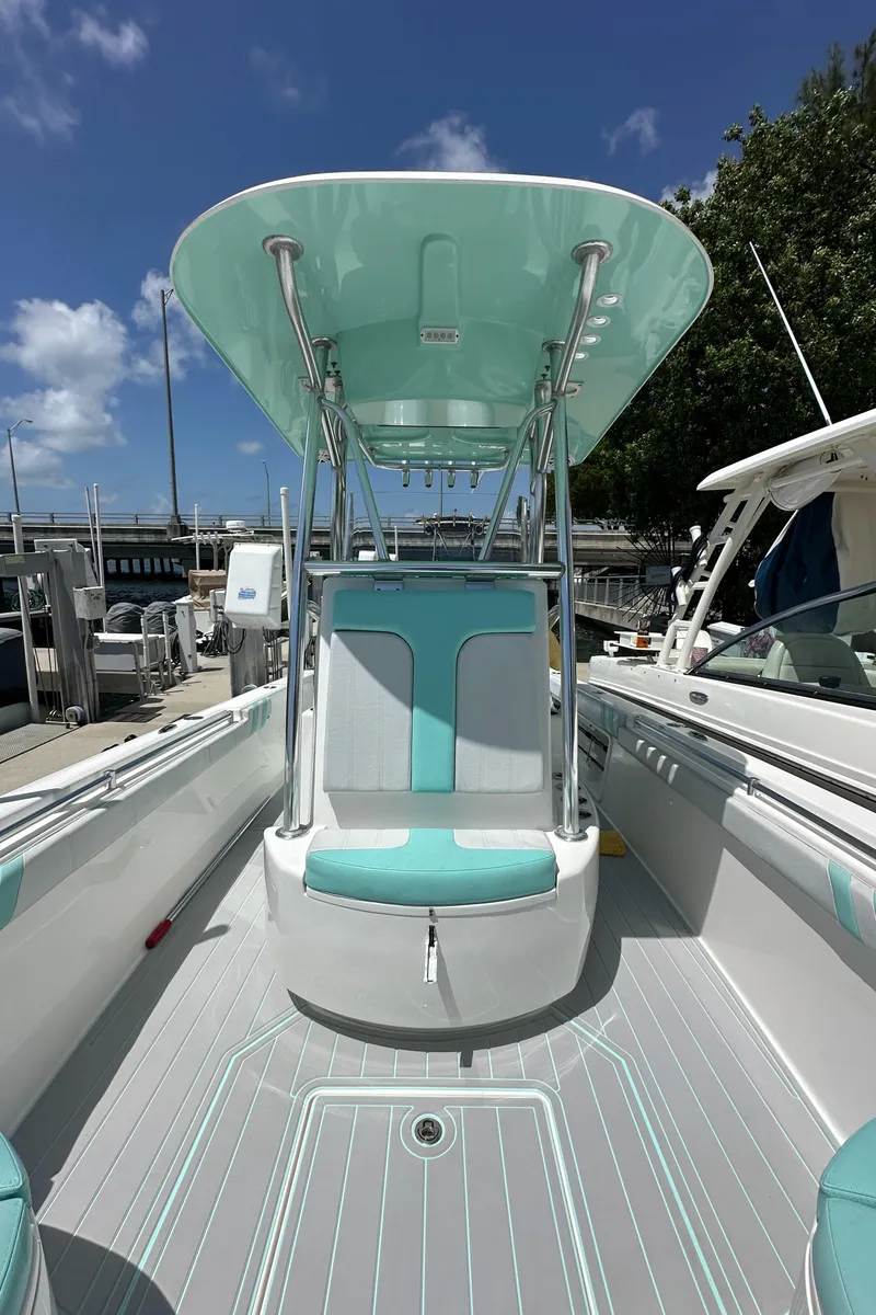Slide: The Image of 2018 Contender 24 Sport boat with teal accents and T-top at marina. - 15