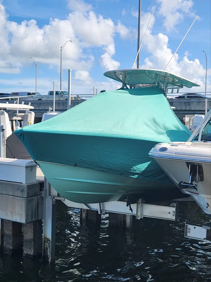 Slide: The Image of 2018 Contender 24 Sport boat covered at dock, under blue sky. - 19