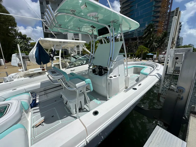 Slide: The Image of 2018 Contender 24 Sport boat docked at marina, featuring center console and T-top. - 2