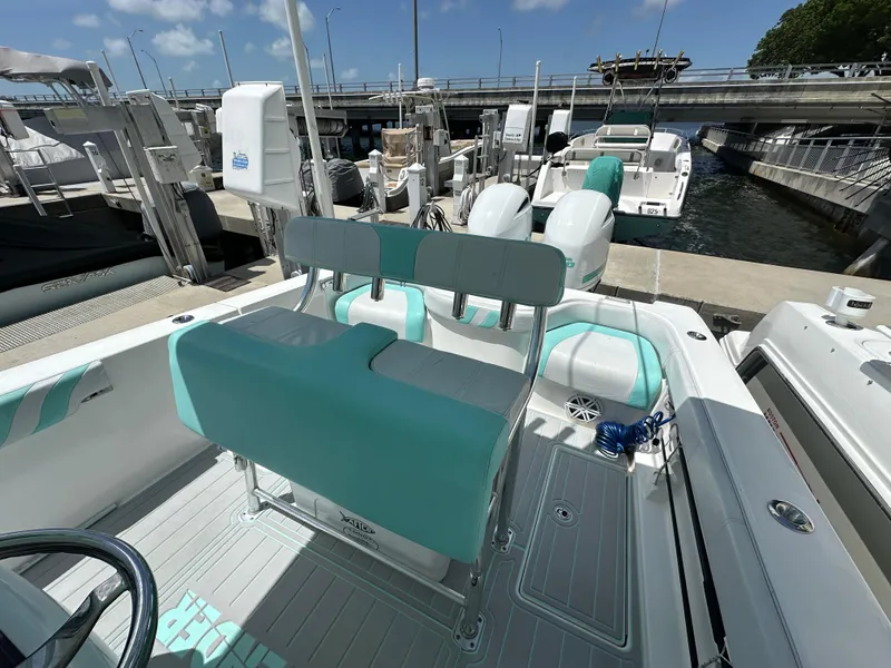 Slide: The Image of 2018 Contender 24 Sport boat with teal and white seating at a marina. - 6