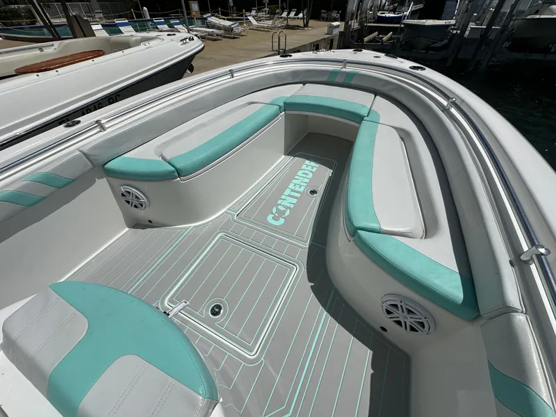 Slide: The Image of 2018 Contender 24 Sport boat with teal and white seating, docked at a marina. - 9