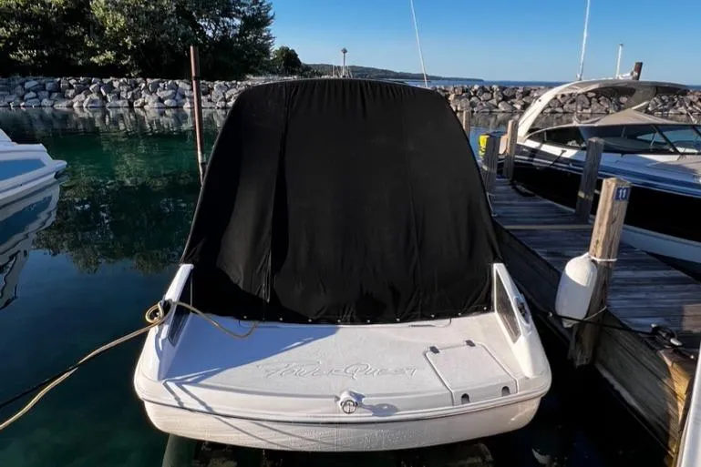 Slide: The Image of 2003 Powerquest 280 SC boat docked with black cover, surrounded by clear water and other boats. - 13