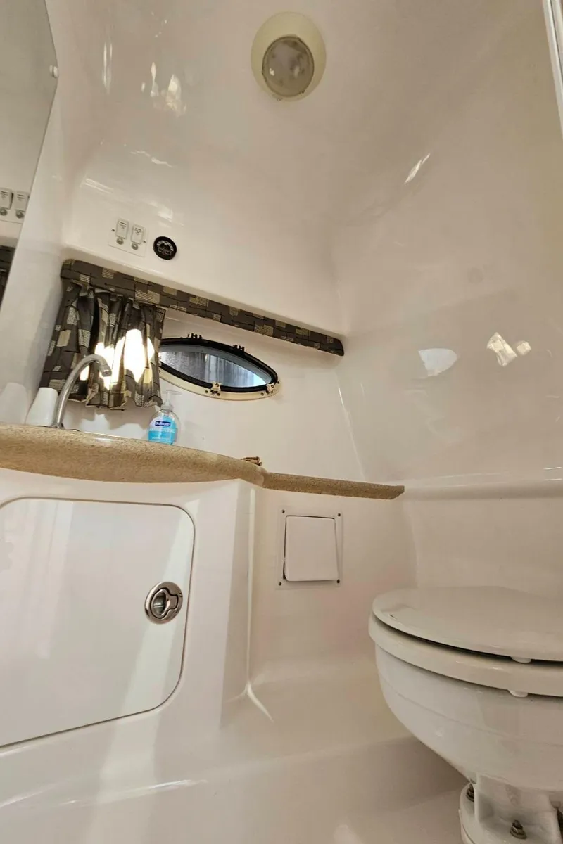 Slide: The Image of 2003 Powerquest 280 SC boat bathroom with sink, toilet, and porthole window. - 21