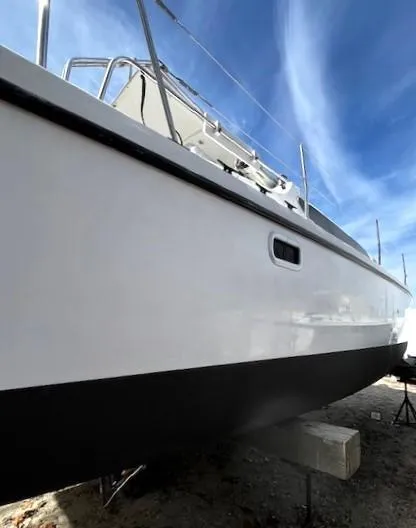 Slide: The Image of 2010 Gemini 105Mc sailboat with sleek white hull, docked under a clear blue sky. - 17