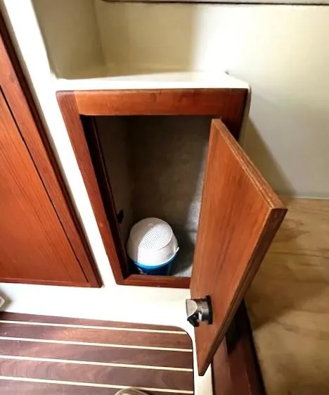 Slide: The Image of Open wooden cabinet on Gemini 105Mc boat, 2010 model, with a white container inside. - 26