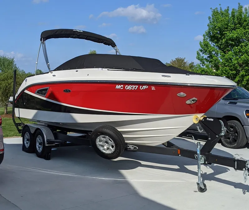 The Image of 2021 Sea Ray SLX 230 boat on trailer, red and white, parked outdoors. - 0
