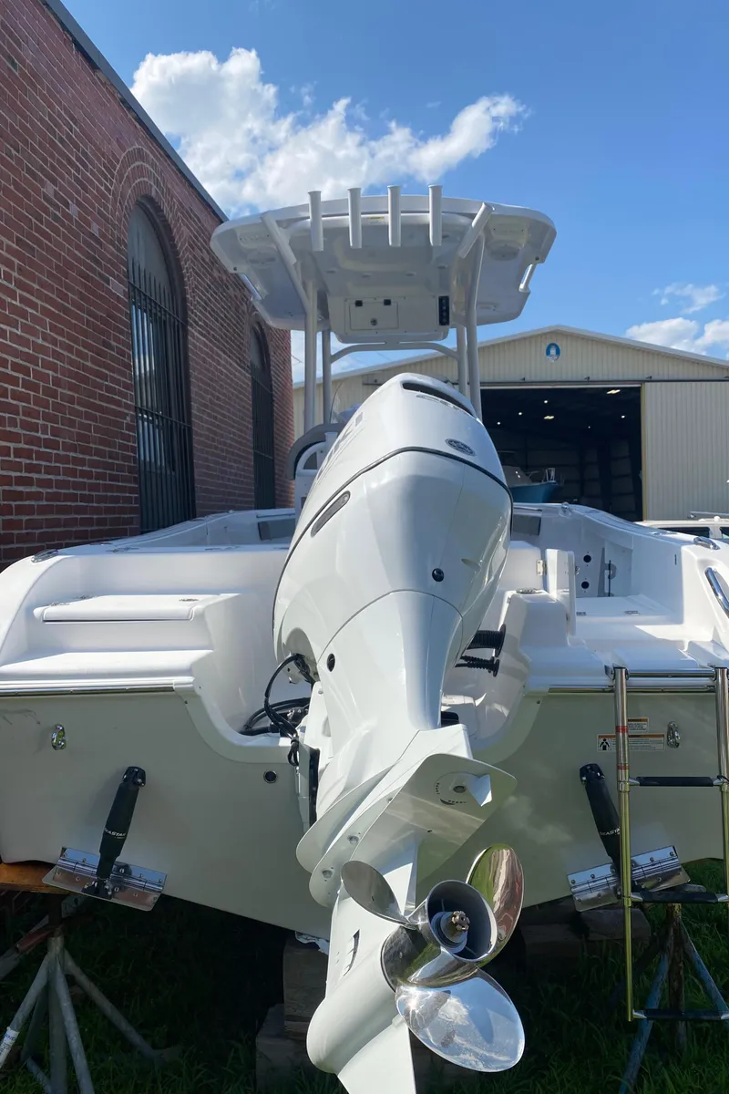 Slide: The Image of 2024 Sea Pro 222 Center Console boat with outboard motor, docked near a brick building. - 2