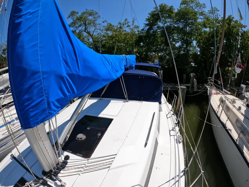 Slide: The Image of 2019 Hanse 388 sailboat with blue sail cover docked near trees. - 15