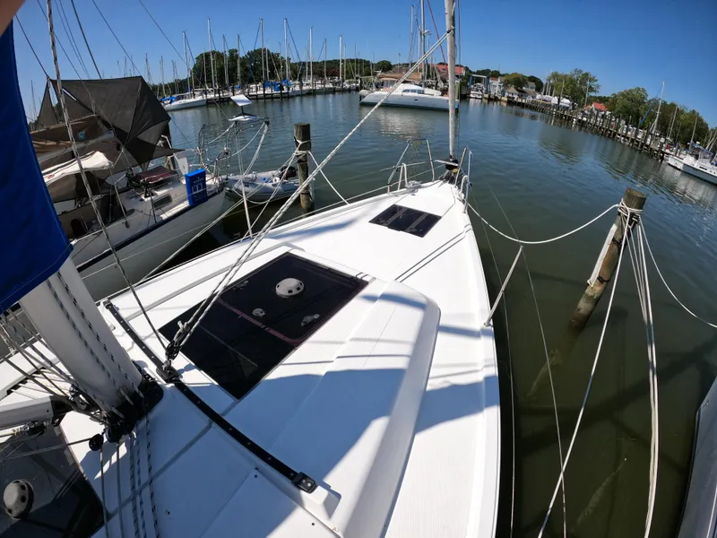 Slide: The Image of 2019 Hanse 388 sailboat docked in a marina, surrounded by calm water and other boats. - 17