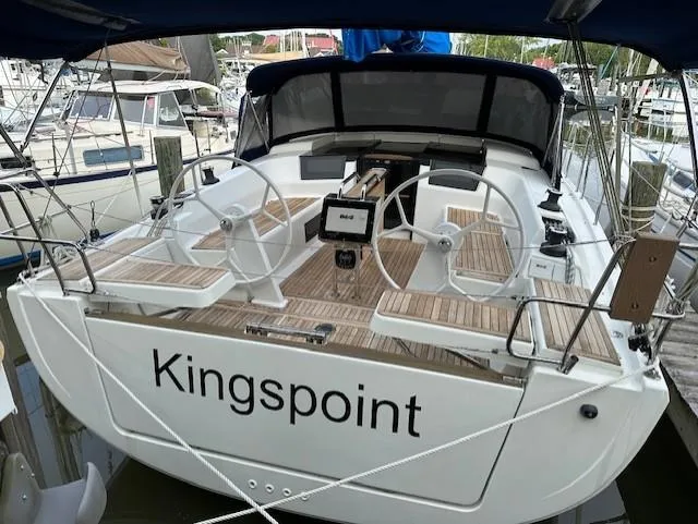 Slide: The Image of 2019 Hanse 388 sailboat "Kingspoint" docked, featuring dual steering wheels and teak deck. - 2