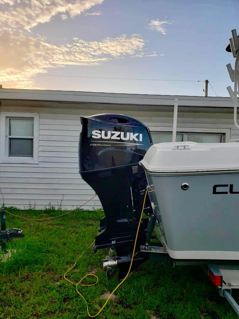 Slide: The Image of Clearwater 2300 boat with Suzuki outboard motor, parked near a house, 2022 model. - 5