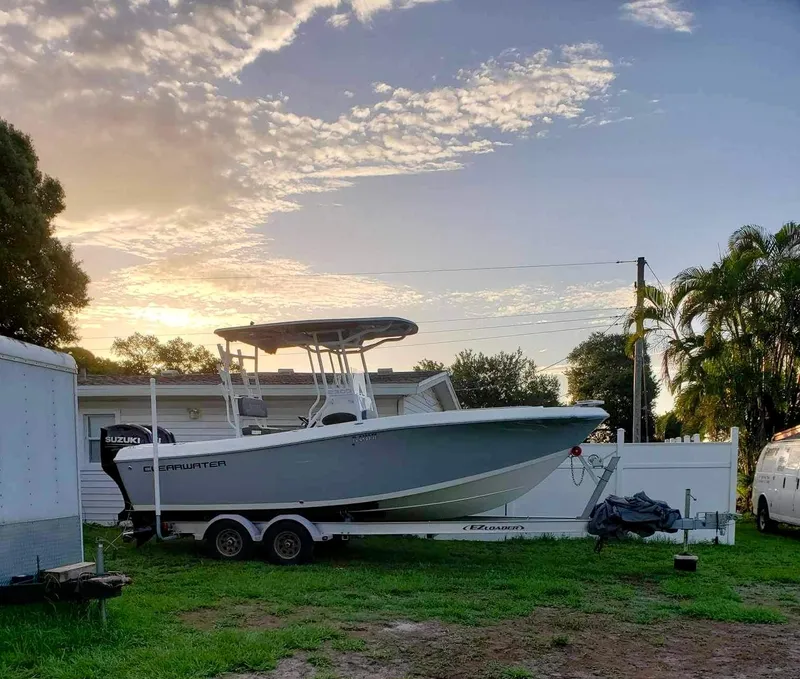 Slide: The Image of 2022 Clearwater 2300 boat on trailer at sunset, parked on grass. - 7