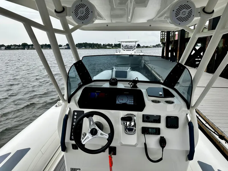 Slide: The Image of 2022 Brig Eagle 8 boat dashboard with steering wheel and controls, docked by the water. - 10
