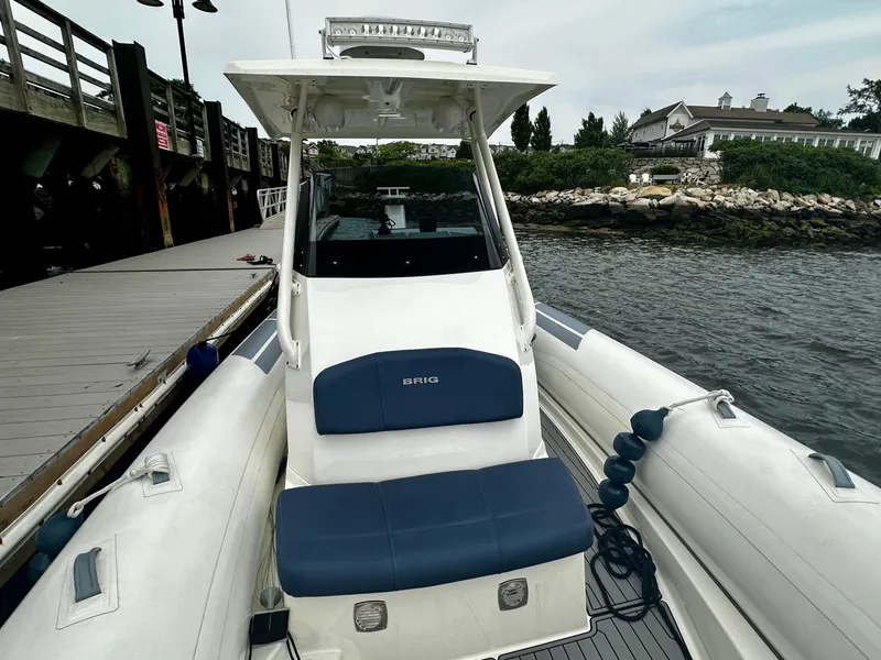 Slide: The Image of 2022 Brig Eagle 8 boat docked by a wooden pier, featuring blue seating. - 13