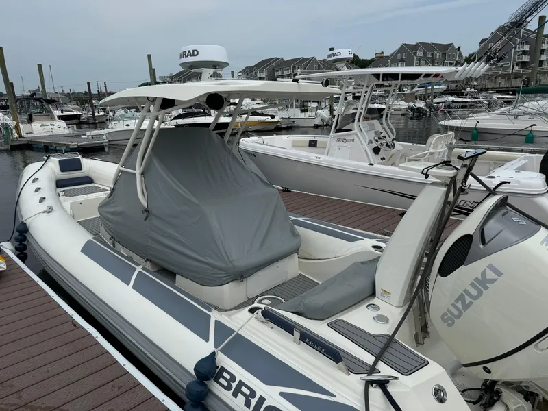 Slide: The Image of 2022 Brig Eagle 8 boat docked, covered, with Suzuki engine, in a marina setting. - 16