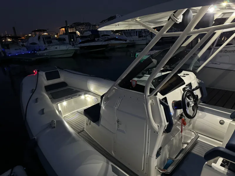 Slide: The Image of 2022 Brig Eagle 8 boat at night, illuminated interior, docked in marina. - 20