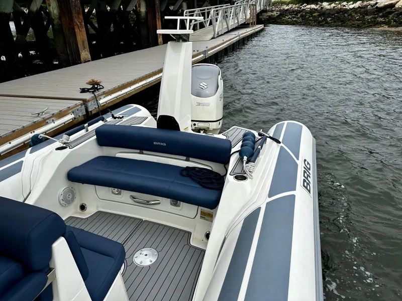 Slide: The Image of 2022 Brig Eagle 8 boat docked, featuring blue seating and a Suzuki outboard motor. - 6