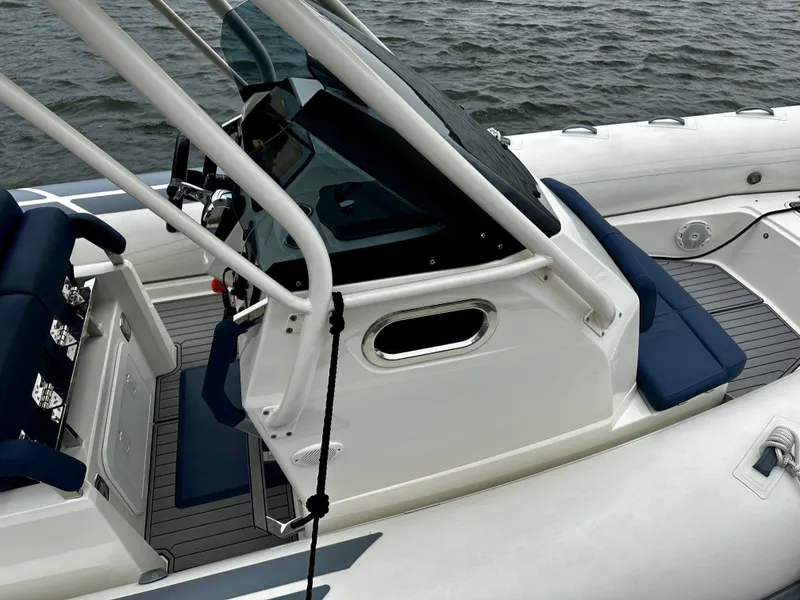 Slide: The Image of 2022 Brig Eagle 8 boat interior with blue seating and control console on water. - 8