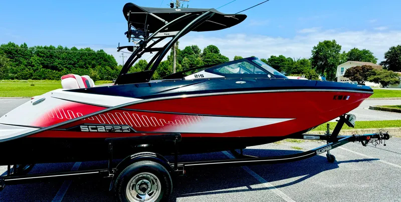 Slide: The Image of 2015 Scarab 215 HO Impulse boat, red and black, on a trailer in a parking lot. - 17