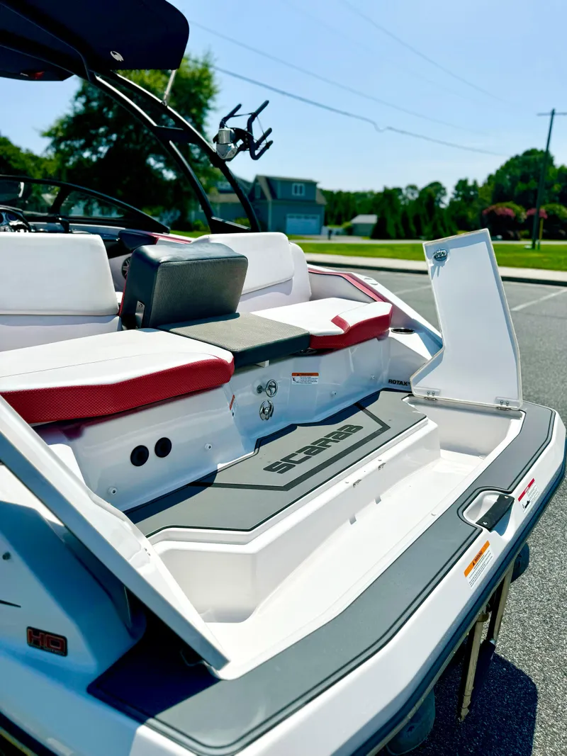 Slide: The Image of 2015 Scarab 215 HO Impulse boat with open storage compartments, parked outdoors. - 26