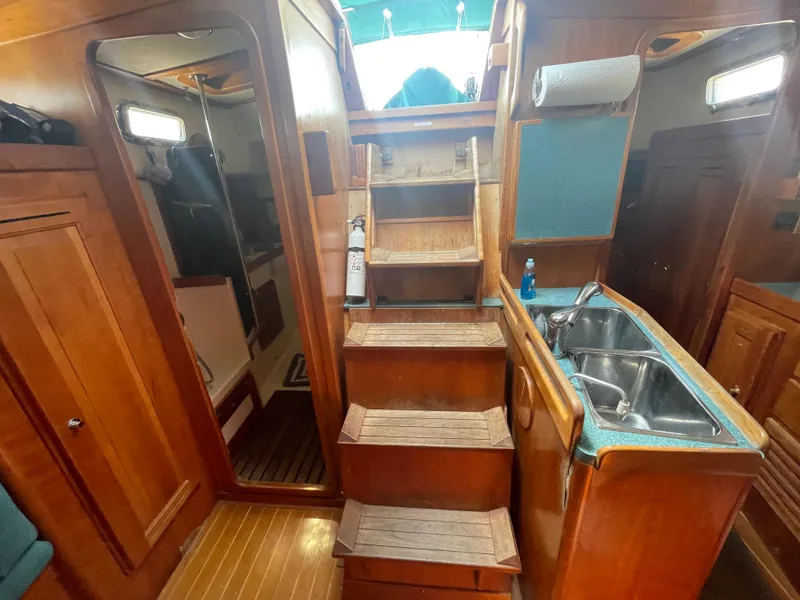 Slide: The Image of Interior of 2001 Tartan 4100 sailboat with wooden stairs and compact kitchen area. - 38