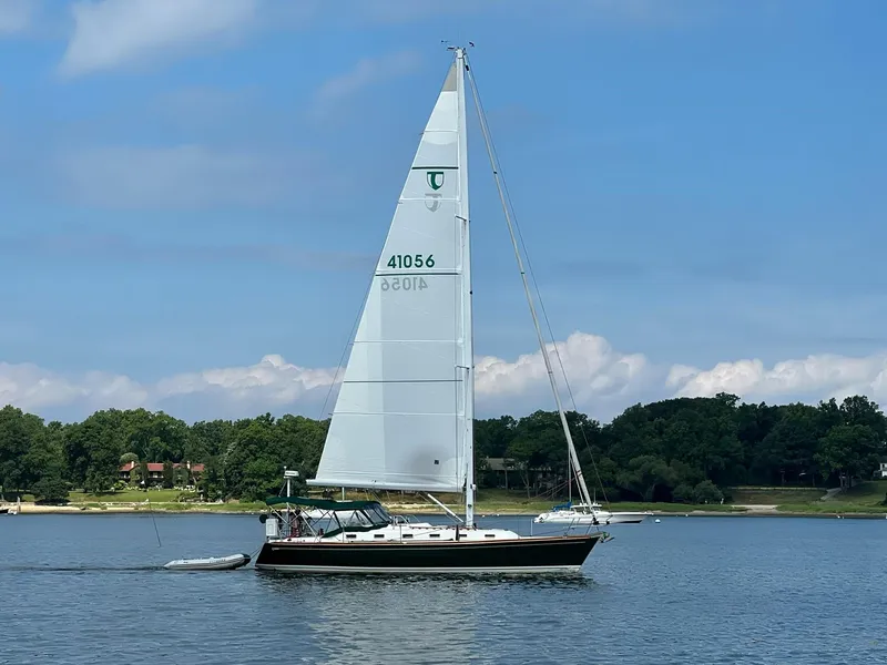 Slide: The Image of Sailing yacht Tartan 4100 (2001) on a serene lake with lush green shoreline. - 4