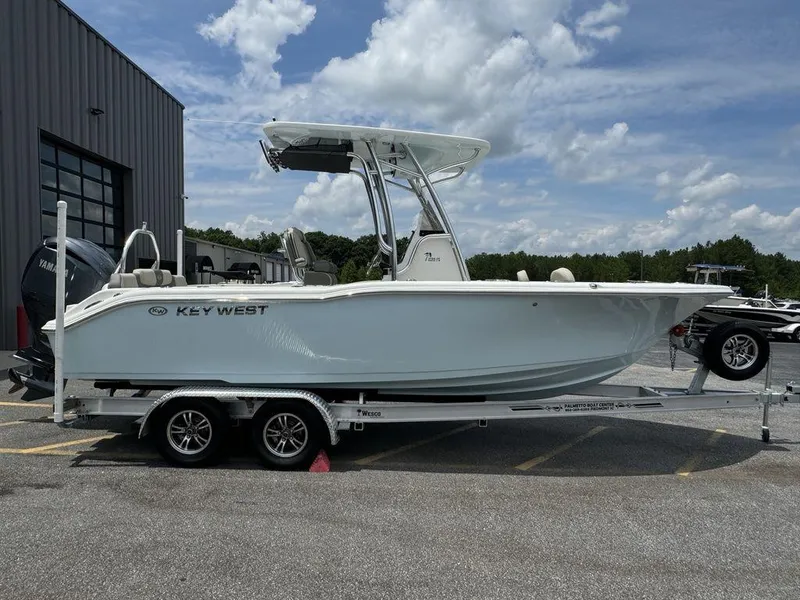 Slide: The Image of 2025 Key West 239FS boat on a trailer outside a warehouse. - 1