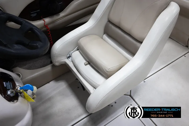 Slide: The Image of 2002 Larson LXI 210 boat interior with steering wheel and white captain's chair. - 21