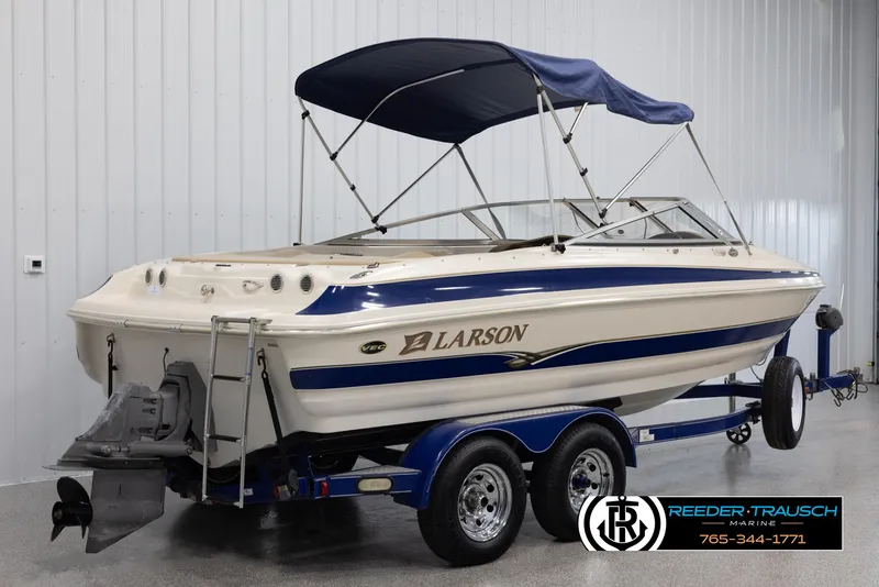 Slide: The Image of 2002 Larson LXI 210 boat with blue and white design on trailer in indoor storage. - 5