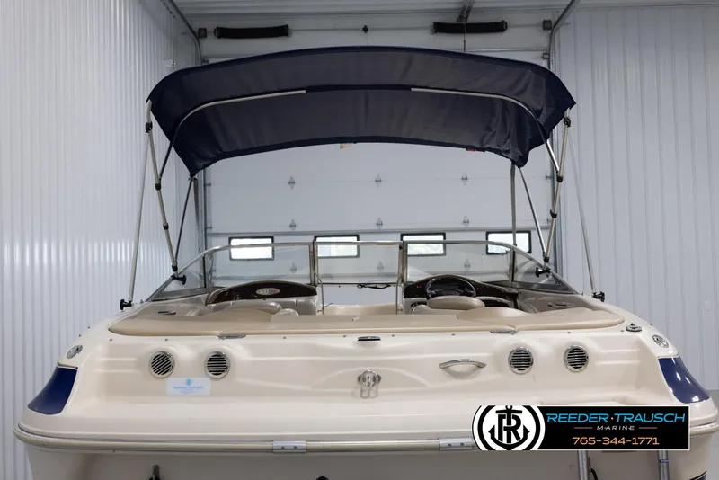 Slide: The Image of 2002 Larson LXI 210 boat with blue canopy in storage. - 6