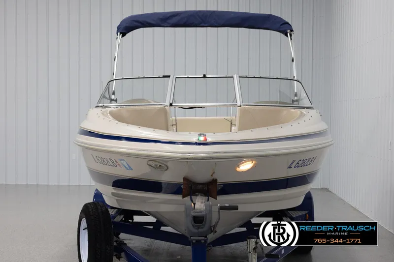 Slide: The Image of 2002 Larson LXI 210 boat with blue canopy on trailer in showroom. - 7