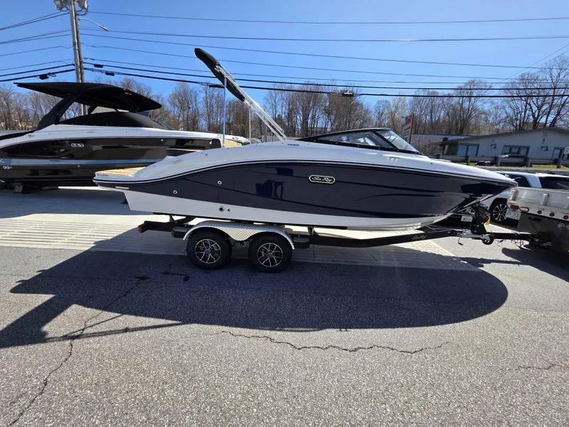 Slide: The Image of 2025 Sea Ray 210SPX boat on trailer, parked outdoors under clear sky. - 1