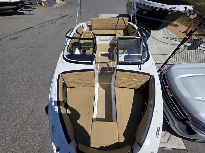 Slide: The Image of 2025 Sea Ray 210SPX boat with tan seating, docked beside vehicles. - 10