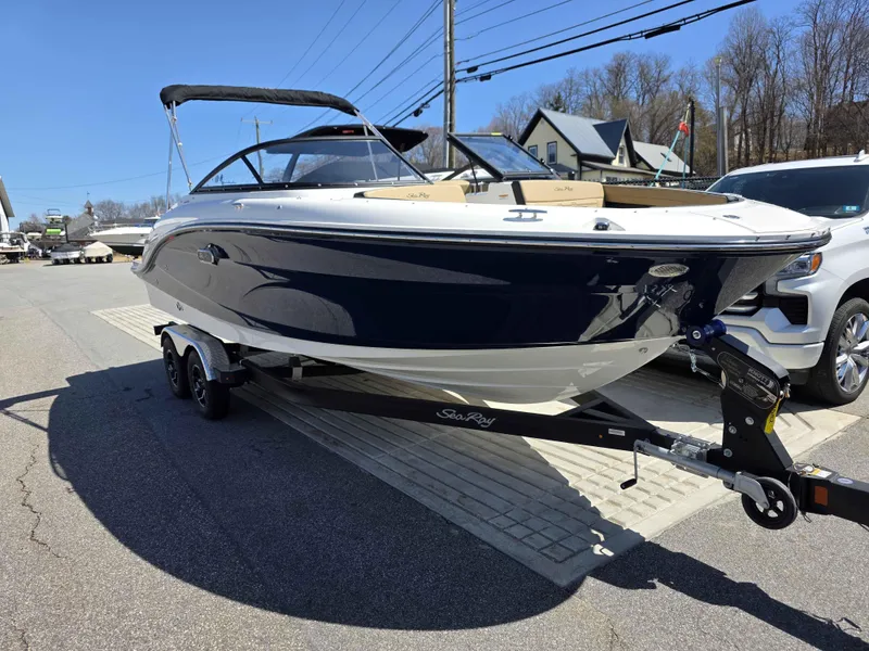 Slide: The Image of 2025 Sea Ray 210SPX boat on trailer, parked outdoors under clear blue sky. - 2