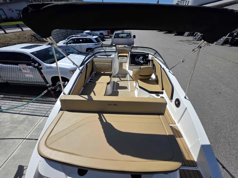 Slide: The Image of 2025 Sea Ray 210SPX boat interior with tan seating and black canopy, parked outdoors. - 3